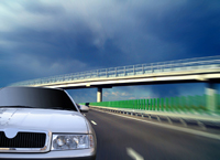 a car driving under a highway overpass under a gray sky